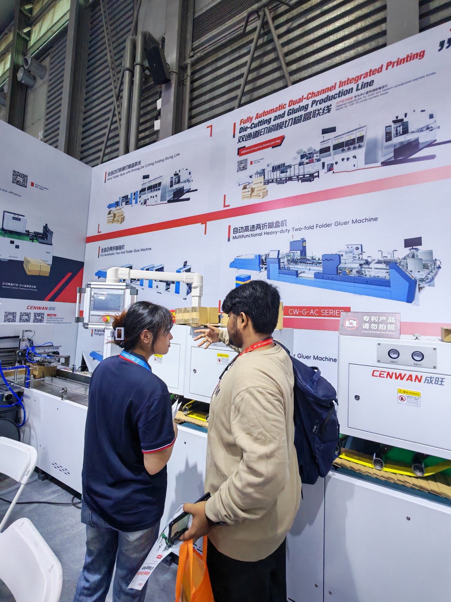 Visitor and Cenwan representative beside a carton-box machine and equipment display